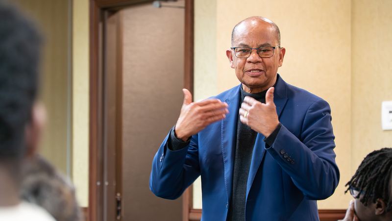 A speaker in a blue blazer talks with the audience