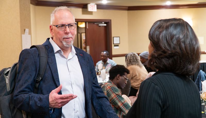 A facilitator talks with an attendee as the room mingles