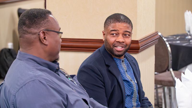 Two community members smile as they talk at a shared table